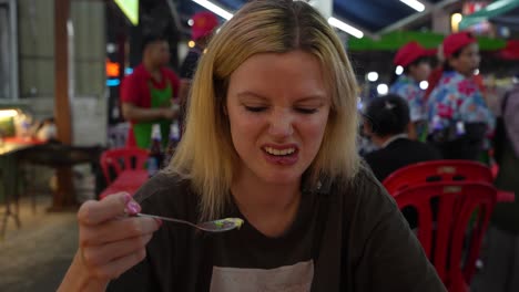 A-young-blonde-woman-makes-faces-while-eating-something-that-tastes-bad