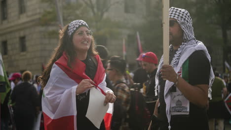 An-Arab-Woman-and-Arab-Man-in-Keffiyehs-Holding-Signs-and-Flags-and-Speaking-at-a-Pro-Palestine-Protest