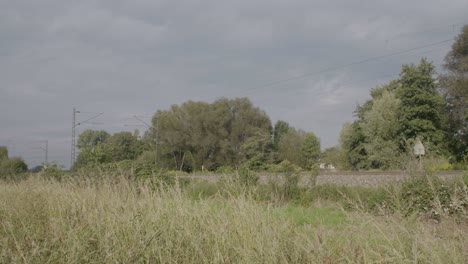 Tren-Rojo-Acelerando-A-Través-Del-Campo,-Cielo-Nublado,-Efecto-De-Desenfoque-De-Movimiento