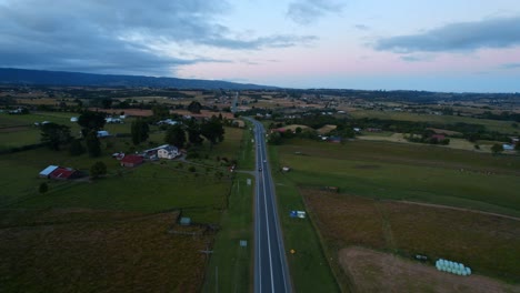 Aerial-Drone-Fly-above-asphalted-highway-through-green-meadow-fields-in-Chile-South-american-transportation,-rural-landscape,-skyline