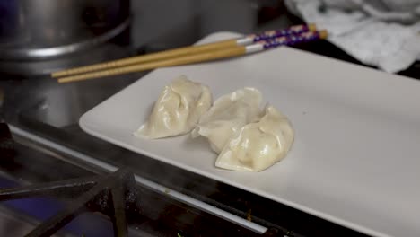 Home-chef-carefully-arranges-hot-steamy-dumplings-on-a-kitchen-tray