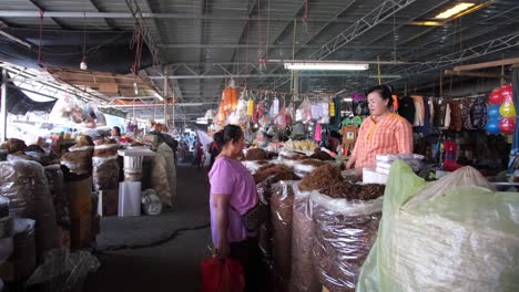 Las-Tomas-De-Fotograma-Completo-Capturan-Una-Exhibición-De-Tabaco-En-El-Mercado,-Con-Dos-Mujeres-Conversando,-Negociando-Y-Charlando-Cerca