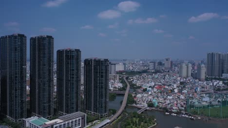 Ho-Chi-Minh-City,-Saigon-River-and-Binh-Thanh-skyline-on-sunny,-clear-day-featuring-landmark-and-golden-river-buildings-from-drone-orbit-shot