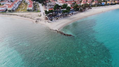 Vista-Aérea-Por-Drones-De-La-Playa-De-Pefkohori-En-Halkidiki,-Grecia,-Demostrando-El-Agua-De-Mar-Azul-Cristalina