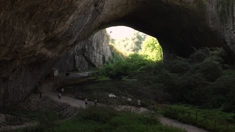 Visitors-walking-through-Devetashka-karst-cave,-spectacular-tourist-attraction-in-Bulgaria