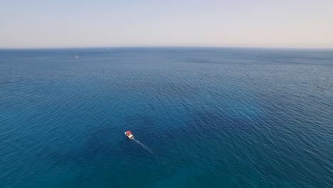 A-small-boat-on-the-crystal-waters-near-oasi-beach-by-keri-caves,-zakynthos,-aerial-view