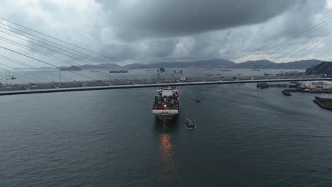 Containerschiff-Nähert-Sich-Unter-Der-Hängebrücke-Des-Steinmetzes,-Filmische-Drohnenaufnahme,-Bewölkter-Himmel