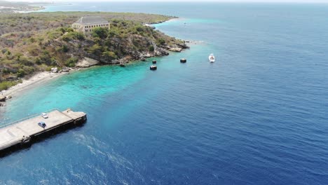 Tugboat-beach-in-curacao-with-clear-blue-waters-and-moored-boats,-aerial-view