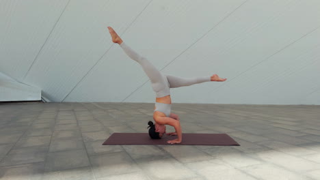 Side-view-of-brunette-woman-performing-Sirsasana-II-yoga-posture-or-headstand-with-variations-of-the-posture