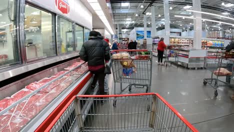 POV---Langsames-Schieben-Eines-Einkaufswagens-An-Kühlvitrinen-Mit-Frischfleisch-In-Großpackungen-Vorbei