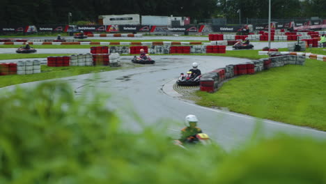 Wet-circuit-kart-track-during-race,-bokeh-from-grass