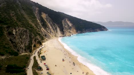 Myrtos-beach-on-kefalonia-island,-showcasing-turquoise-waters-and-white-sands,-with-a-mountain-backdrop,-aerial-view
