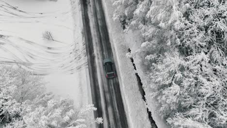 Drohnenaufnahmen-Von-Einem-Auto,-Das-Auf-Einer-Winterlichen-Waldstraße-Fährt