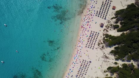 Strand-Von-Cala-Agulla-Mit-Türkisfarbenem-Wasser-Und-Lebhaften-Strandbesuchern-An-Einem-Sonnigen-Tag,-Nahaufnahme,-Luftaufnahme