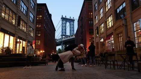 Couple-Embrace-With-A-Dip-In-New-York-City,-Brooklyn-Bridge-In-Background