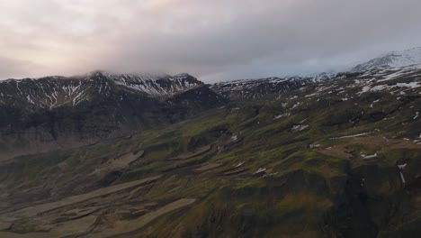 Aerial-landscape-view-of-icelandic-mountain-peaks-covered-in-melting-snow,-on-a-cloudy-evening