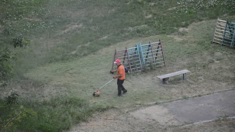 KYIV,-UKRAINE---JULY-23,-2020:-Male-worker-cuts-the-lawn-with-a-gasoline-trimmer