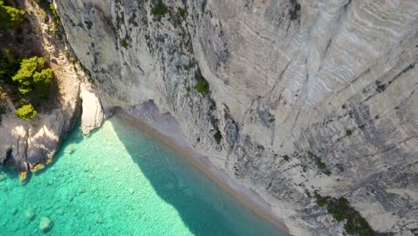 Oasi-beach-near-keri-caves-in-zakynthos,-greece,-showcasing-turquoise-waters-and-steep-cliffs,-sunny-day,-aerial-view