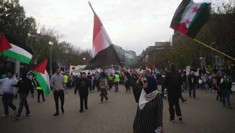 A-Slow-Motion-Shot-of-an-Arab-Woman-Waving-a-Yemeni-Flag-in-Front-of-a-Large-Crowd-of-Pro-Palestine-Protestors-Marching-in-the-Streets