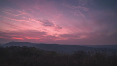 Zeitraffer-Von-Tag-Zu-Nacht-Eines-Farbenfrohen-Abendhimmels-In-Der-Dämmerung,-Der-In-Eine-Sternenklare-Nacht-übergeht,-Mit-Einer-Hügeligen-Landschaft-Und-Dem-Mond-Im-Vordergrund