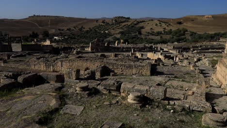 Antiguas-Ruinas-Romanas-En-Dougga-Bajo-El-Cielo-Azul-Claro,-Sombras-Proyectadas-Sobre-El-Sitio-Histórico