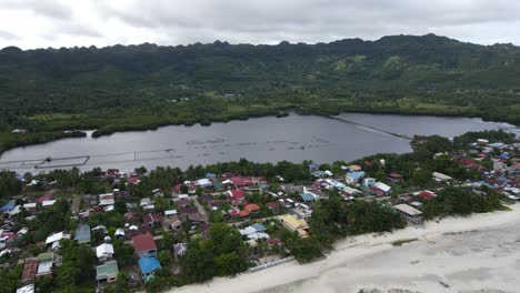 Drones-Aéreos-Vuelan-Sobre-La-Ciudad-Costera-De-Anda-En-Filipinas-Con-Casas-Y-Verdes-Colinas-Tropicales