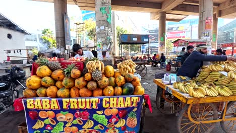 Comerciantes-Indios-Que-Venden-Chaat-De-Frutas-Religiosas-Mientras-Se-Quema-Incienso-De-Shivling-Cerca-De-La-Estación-De-Metro-De-Sikanderpur,-Gurgaon,-India