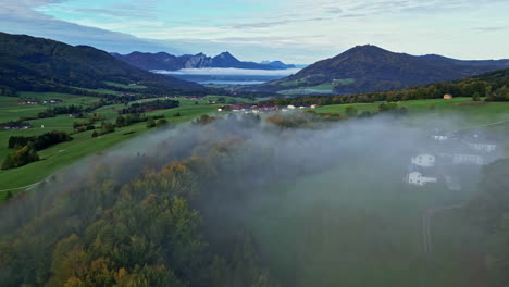 Malerische-Aussicht-Mit-Nebelschicht-über-Der-Landschaft-Mit-Bergigem-Hintergrund-In-Einer-Grünen,-üppigen-Umgebung,-Luftaufnahme