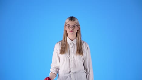 Una-Joven-Caucásica-Juega-A-Lanzar-Una-Pelota-Con-Camisa-Blanca-Y-Gafas-Inteligentes-Rubia-Nórdica-Hermosa-Mujer,-Fondo-Azul-Croma-Profesional-De-Estudio,-Torso