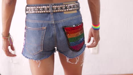 Junger-Mann-Posiert-In-Farbenfrohen-Regenbogendetails-Im-LGBTQ-Thema-Und-Zeigt-Pride-Outfit