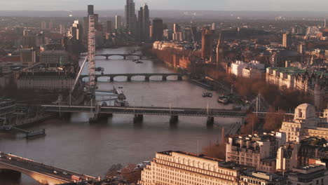 Toma-Aérea-Deslizante-De-La-Casa-Del-Parlamento-Y-El-Ojo-De-Londres-En-El-Támesis-Al-Amanecer