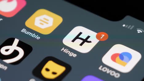 Smartphone-screen-with-focus-on-Hinge-app-icon,-one-new-notification,-other-dating-apps-blurred