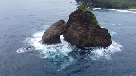 Aerial-arc-around-rock-islet-in-ocean,-Siargao,-Magpopongko