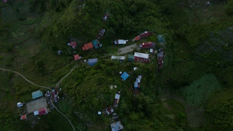 A-remote-village-nestled-in-the-lush-green-mountains-of-the-philippines-at-dusk,-aerial-view