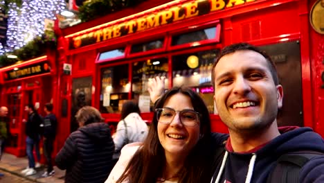 Smiling-couple-selfie-with-the-vibrant-Temple-Bar-pub-in-background,-Dublin