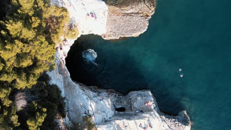 Swimming-by-Galebijana-Cave-Pula-Island---Aerial-Drone-Shot