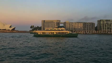 Sunset-view-of-a-Sydney-Harbour-ferry-near-the-Opera-House,-warm-hues-reflecting-on-water