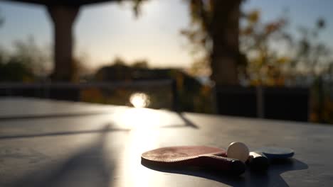 Mesa-De-Ping-Pong-Con-Palas-Situada-En-Una-Terraza-En-Cannes,-Francia,-Con-El-Sol-Brillando,-Primer-Plano-Con-Cámara-En-Mano