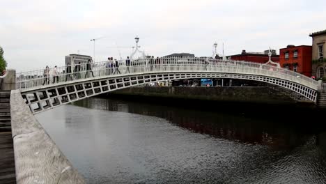 People-crossing-pedestrian-Ha'Penny-Bridge-over-Liffey-River-in-Dublin