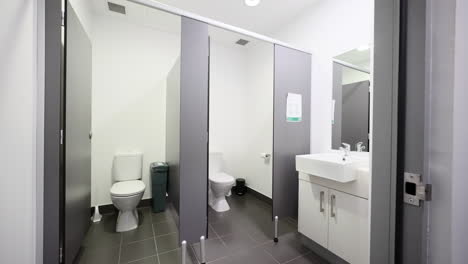 Öffentliche-Damentoilette,-Sauberes,-Graues-Interieur-Mit-Privaten-Kabinen-Und-Hygieneabfallbehälter