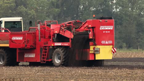 Heavy-machinery-crop-harvester-in-farmland-soil-entering-the-frame