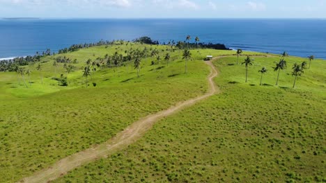 Surreal-island-landscape-of-winding-trail-on-lawnlike-rolling-hills,-Aerial