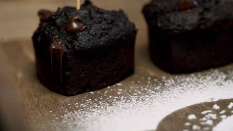 Zoomen-In-Einen-Schokoladen-Rüben-Muffin-Mit-Geschmolzenen-Schokoladenstückchen-Und-Puderzucker-Daneben