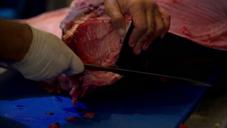 Slow-motion-close-up-of-a-male-chef-slicing-and-cutting-the-skin-off-of-a-fresh-blue-fin-tuna