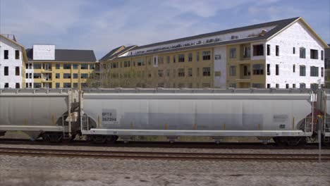 Drohnenansicht-Des-Neubaus-Von-Wohnhäusern,-Während-Der-Zug-Vorbeifährt