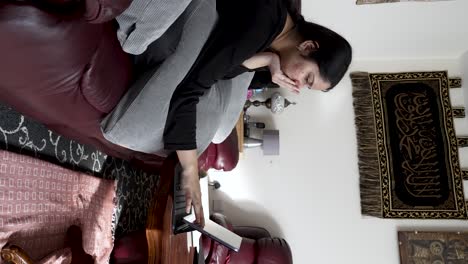Britisch-asiatische-Weibliche-Teenager-Tippen-Auf-Dem-IPad,-Während-Sie-Bequem-Auf-Dem-Sofa-Sitzen