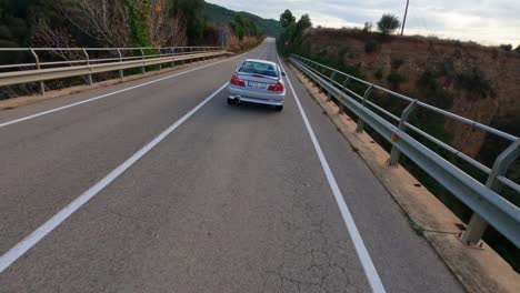 Un-Drone-FPV-Sigue-De-Cerca-A-Un-Coche-Deportivo-Sobre-Un-Puente.