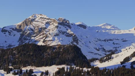 Aerial-shot-at-dawn-showcasing-the-silhouette-of-a-snowy-mountain-range