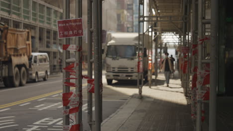 Static-shot-of-pedestrians-walking-on-sidewalk-covered-by-scaffolding-in-city