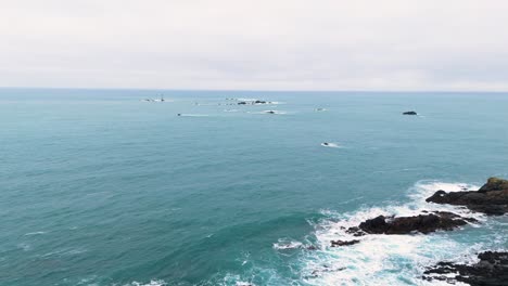 Flight-from-Pleinmont-towards-Hanois-Lighthouse-Guernsey-over-cliffs-and-out-to-sea-on-bright-cloudy-day-with-rocks-and-sea-spray